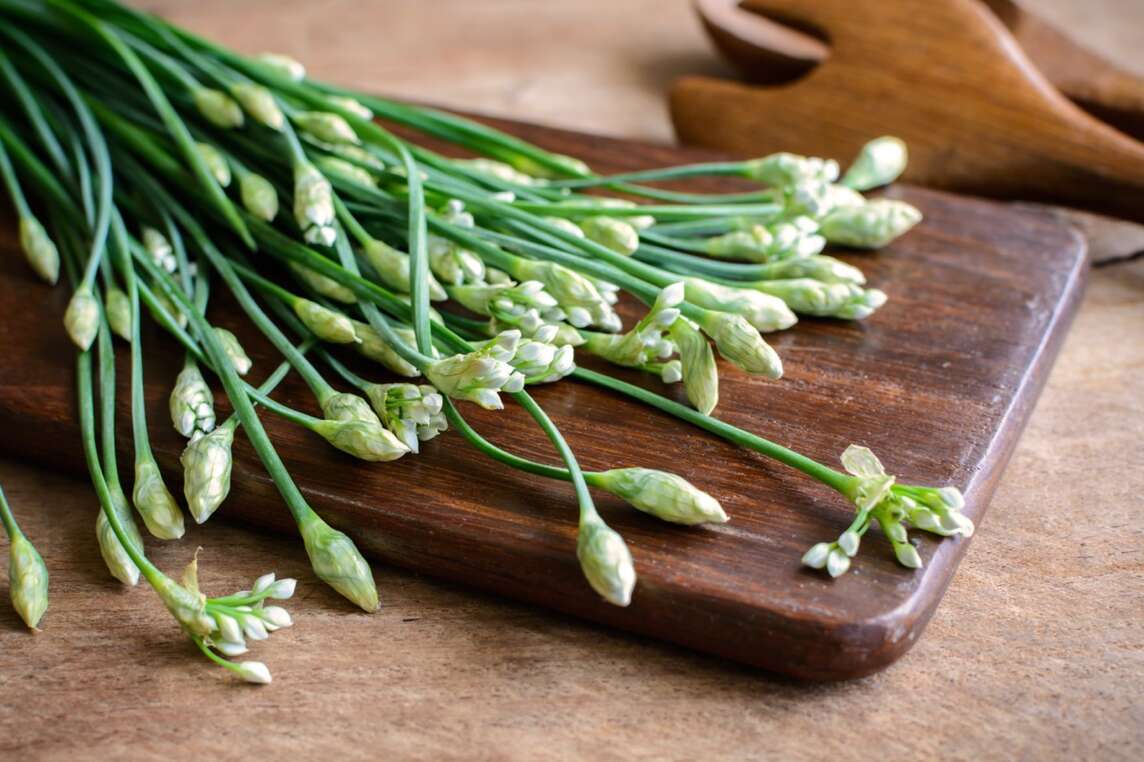 Tagliare i gambi e i fiori dell'aglio sul tagliere